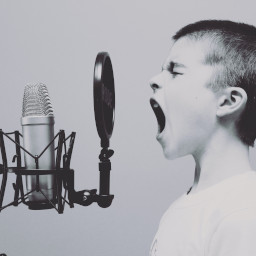 Photo of a child screaming into a microphone in a recording studio